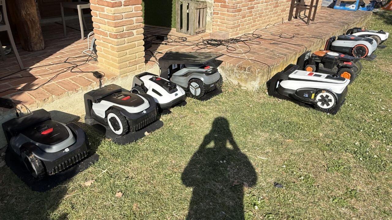 Diverse Mähroboter ohne Begrenzungsdraht, mit LiDAR, KI-Kamera und anderen Innovationen stehen im Test und Vergleich nebeneinander in den Stationen